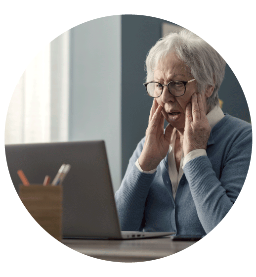 elderly woman with hands on cheeks as she looks at her laptop in shock