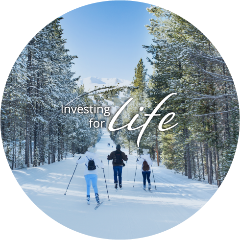 Investing for Life text over image of family cross country skiing down path between trees with a snow capped mountain off in the distance
